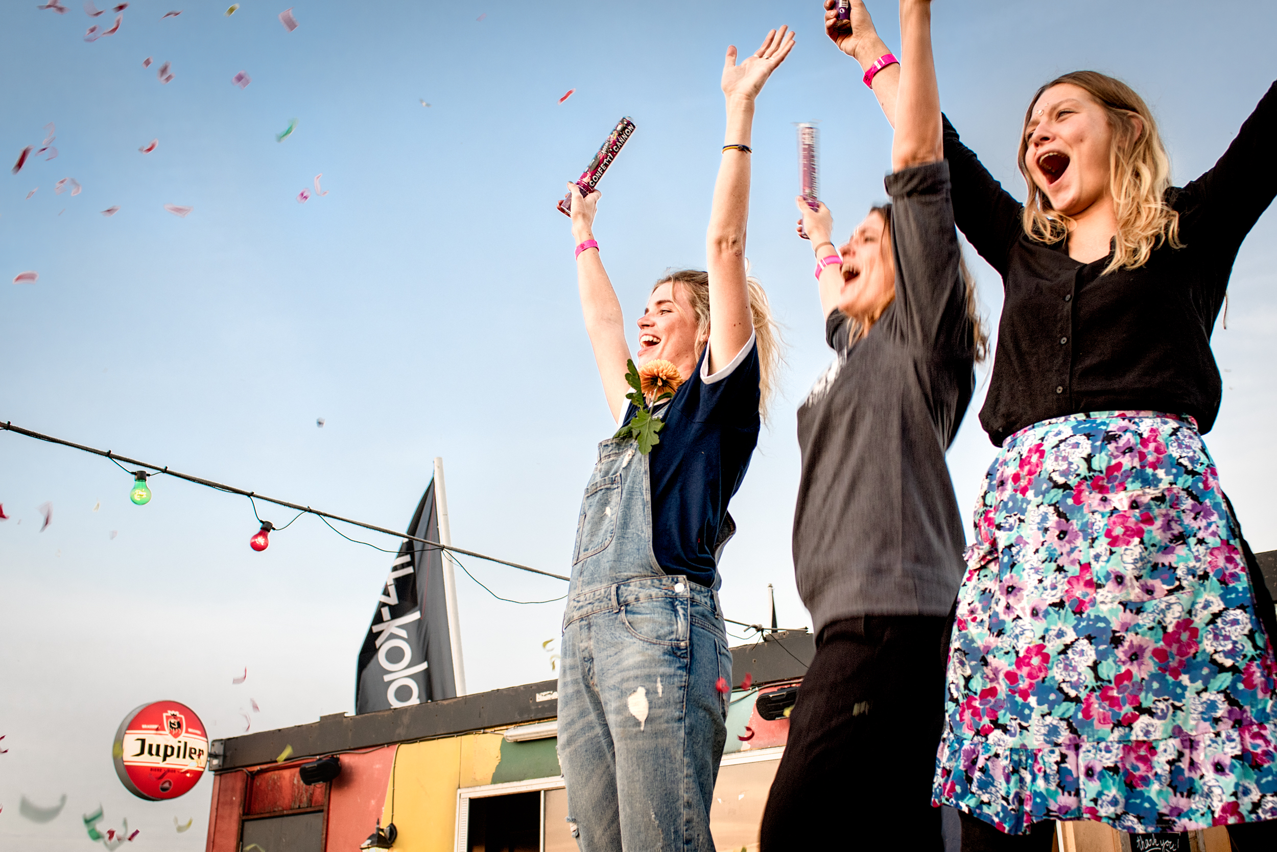 three women cheering with arms raised, flags flying