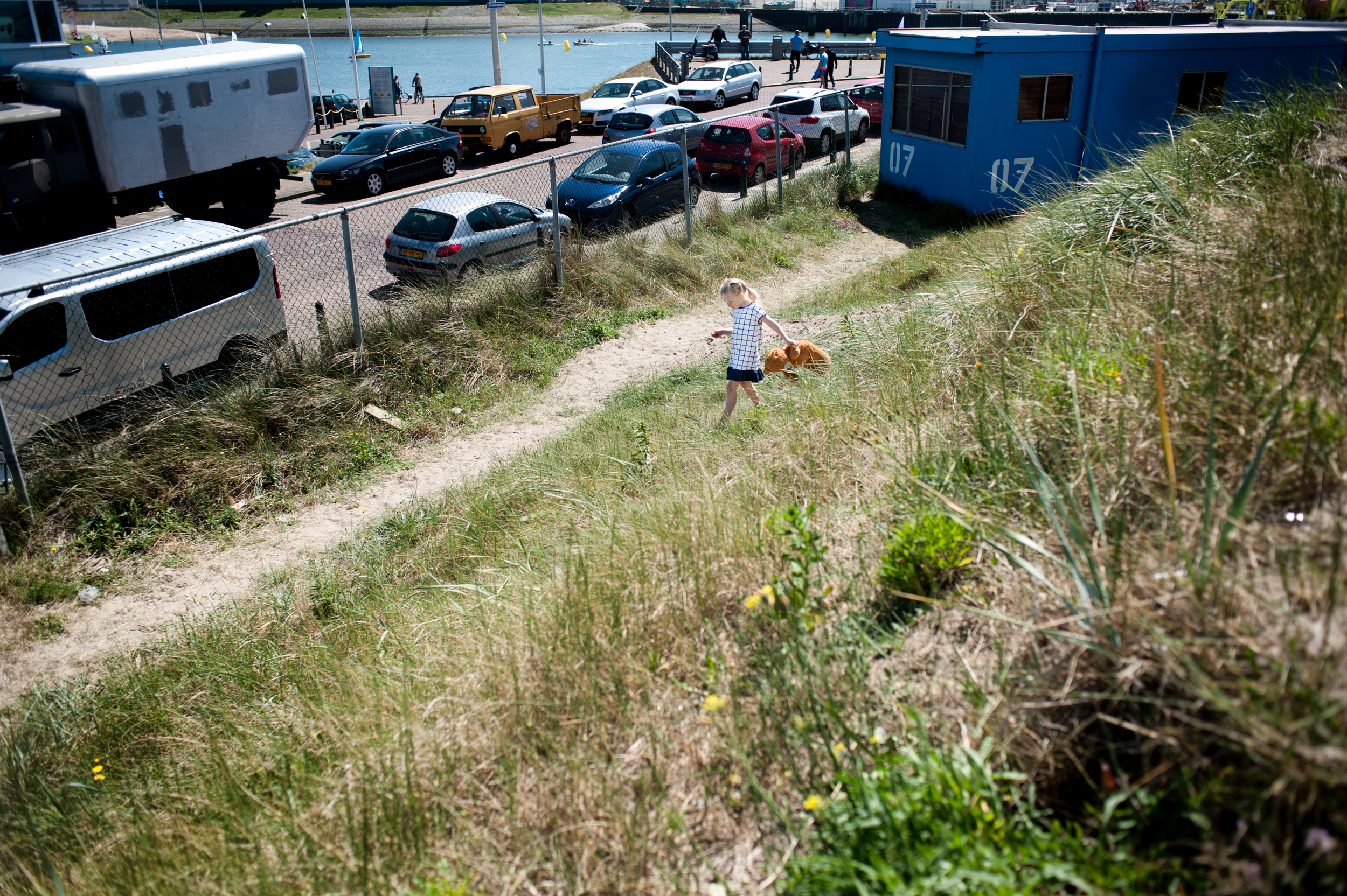 little girl with Teddy bear walking among the caravans on the grass
